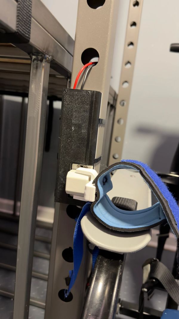Close up of the solenoid attached to the squat rack, along with the cuff attached to the solenoid.